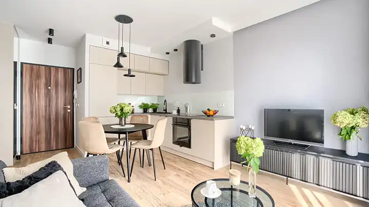 Salon z aneksem kuchennym w jasnej aranżacji z drewnianą podłogą