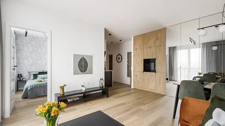 Salon z telewizorem, drewnianą zabudową i jasnymi ścianami