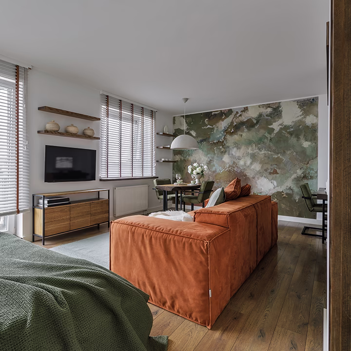 Nowoczesne wnętrze salonu z pomarańczową sofą i artystyczną ścianą.