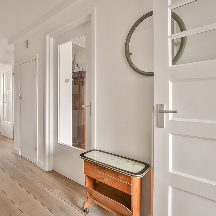 Jasny korytarz, minimalistyczny design wnętrz Warszawa, drewniana podłoga, lustro.